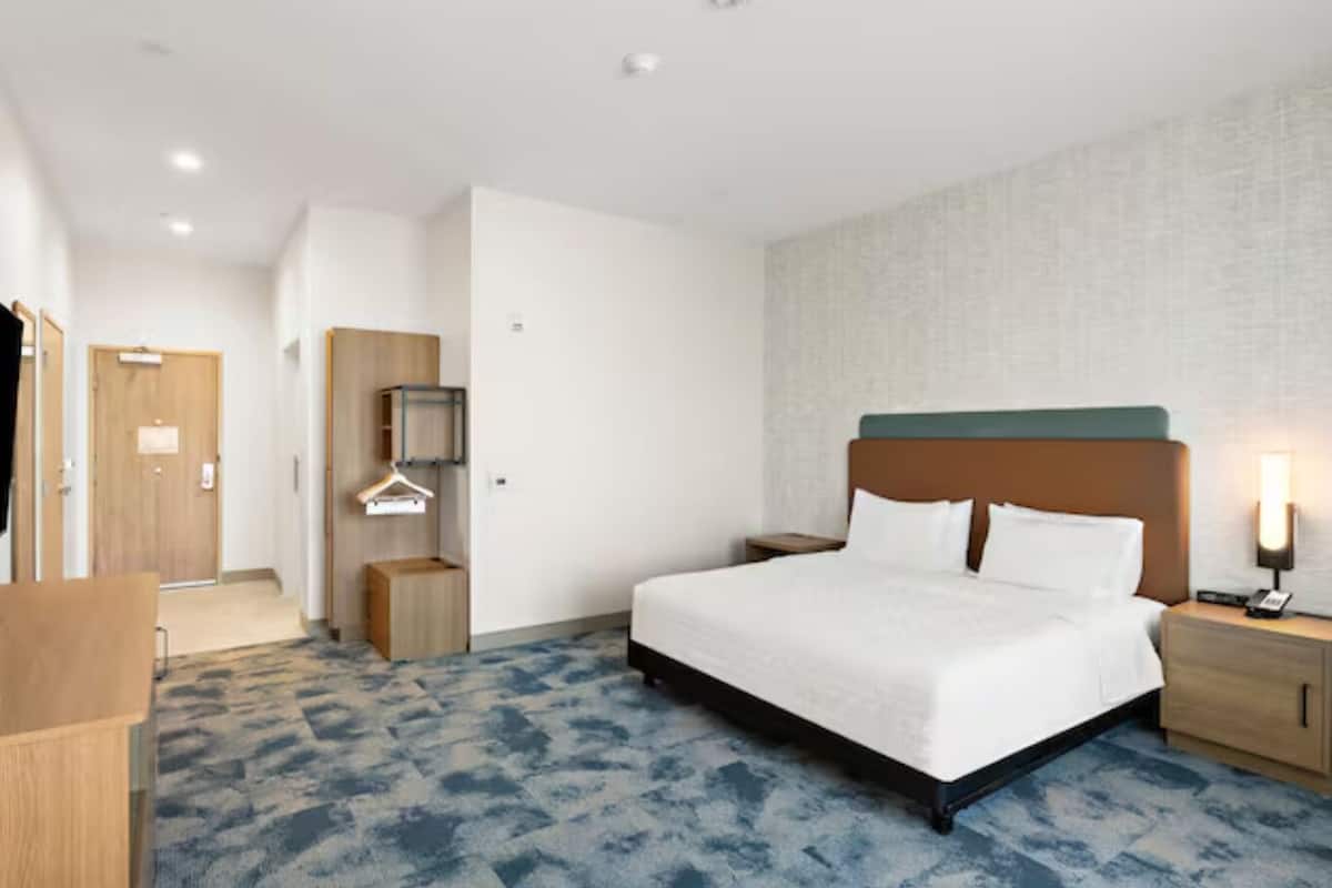 Een hotelkamer met een bed, nachtkastjes, een televisie, een kledingkast en een spiegel.