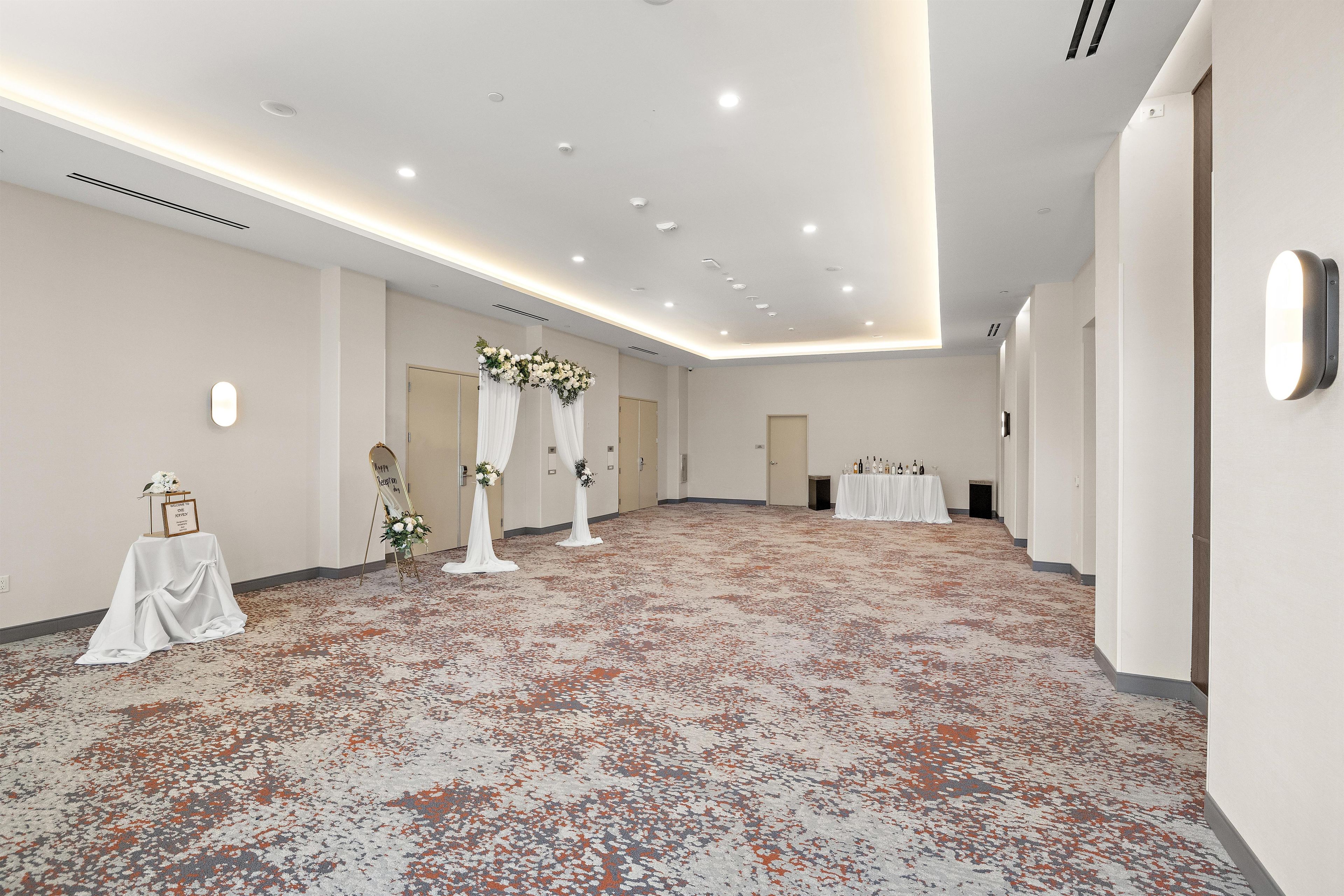 A spacious hotel room with a carpeted floor, a reception desk, and a reception area with a floral arrangement.