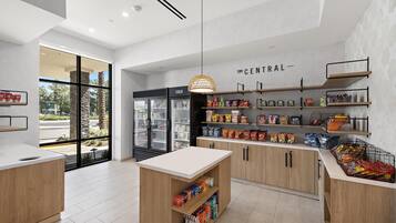 Un bar de aperitivos moderno y bien iluminado con una variedad de productos envaselados y un mostrador refrigerado.