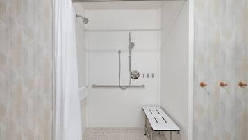 Zona de ducha con cabezal de ducha de mano, grifo empotrado en la pared y un perchero.