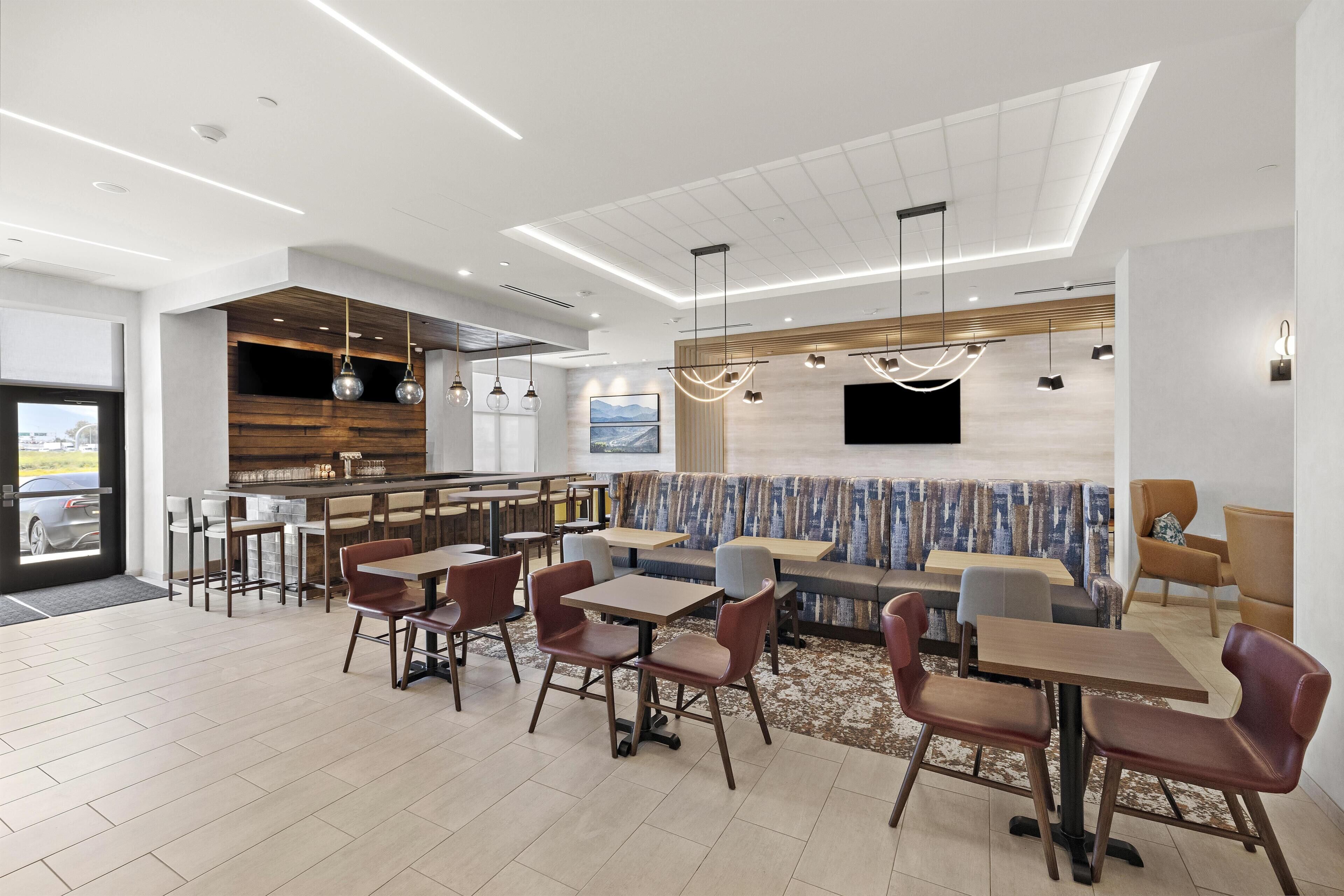 A modern restaurant with a bar area, seating arrangements, and a large window.