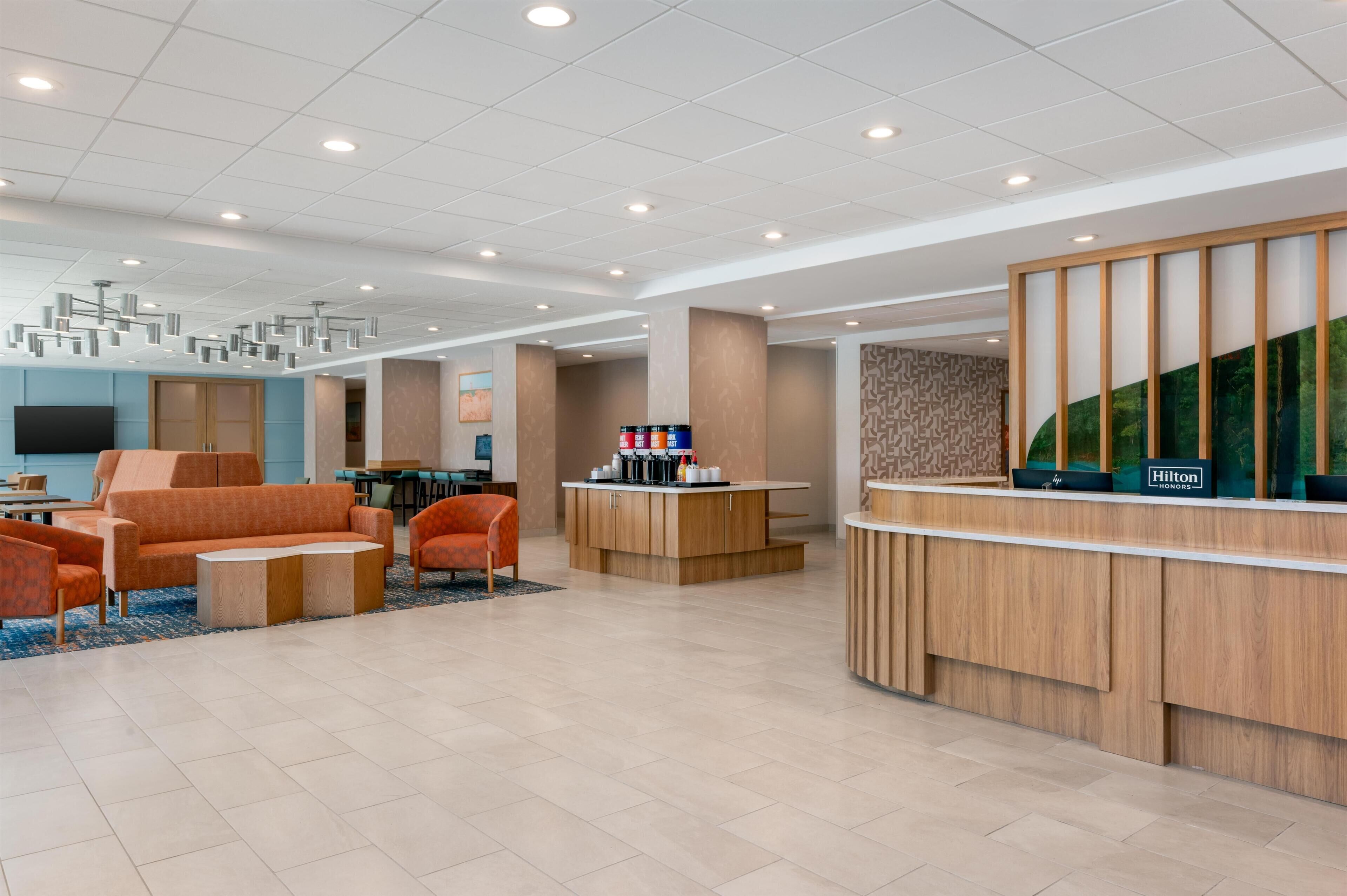 A hotel lobby with a reception desk, seating area, and a television.