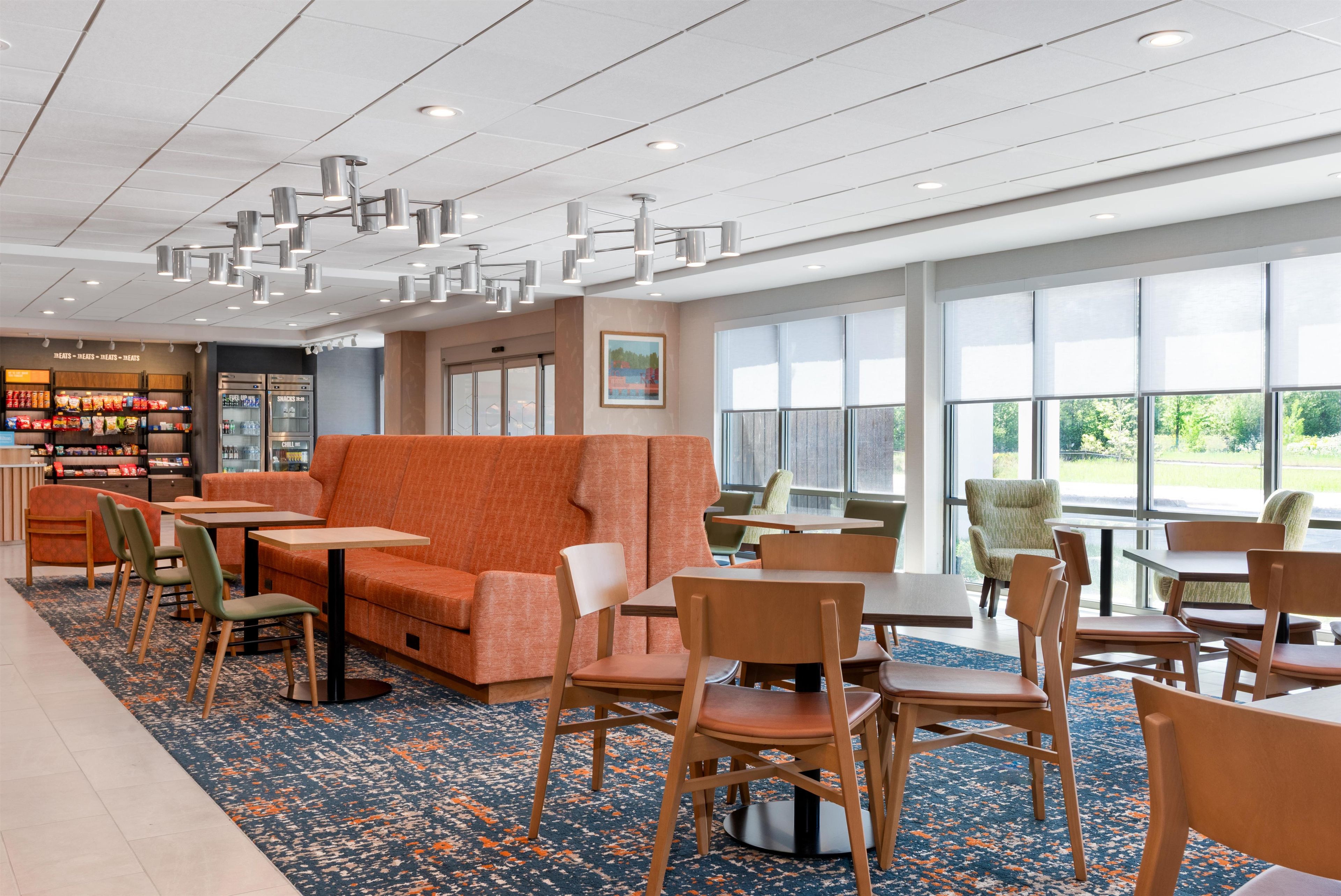 A modern dining area with orange seating, wooden tables, and chairs.