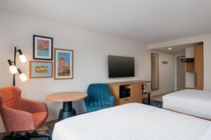 A hotel room with two beds, a desk with a flat-screen TV, a chair, and a table. - Hampton Inn & Suites Cadillac (Cadillac)