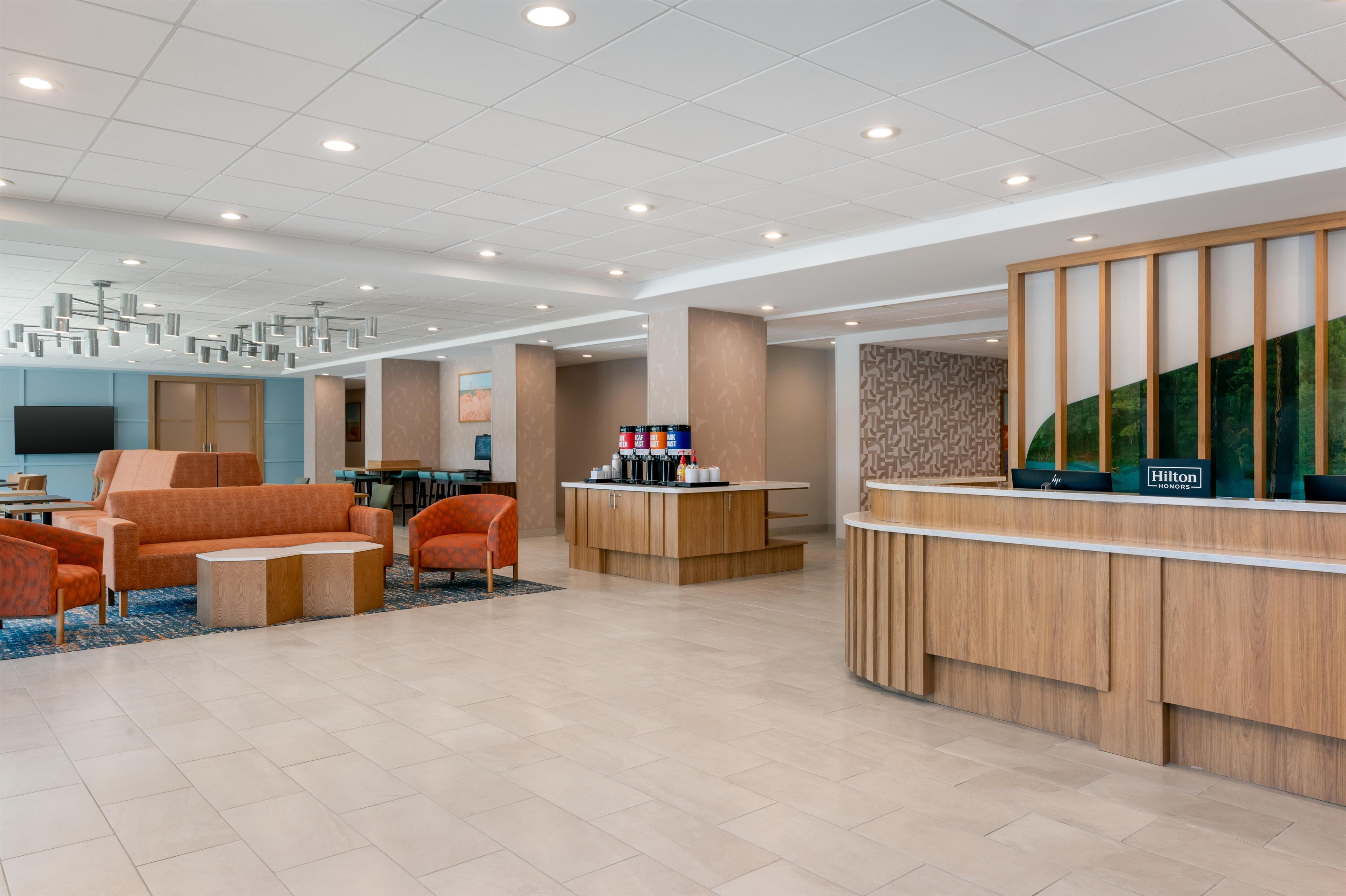 A hotel lobby with a reception desk, seating area, and a television.