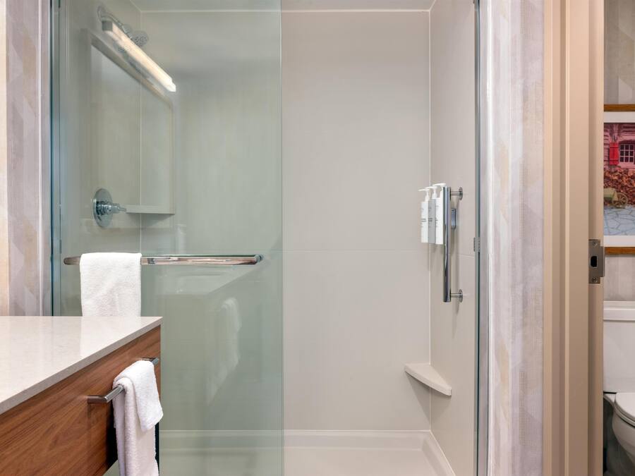A modern bathroom with a glass shower enclosure, a white toilet, and a wooden vanity.