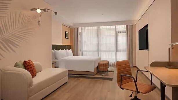 Una habitación de hotel con una cama, un sofá, un escritorio y un televisor.