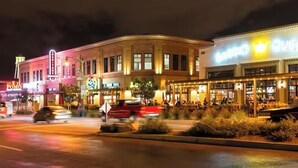 A street view at night with illuminated buildings, including a restaurant with outdoor seating and a brightly lit sign. - Cozy Cottage in Downtown Gilbert Heritage District Sleeps Up To 3 (Gilbert)