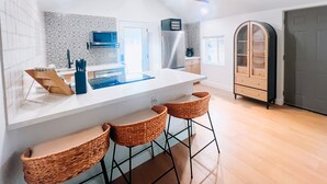 A modern kitchen with a central island, bar stools, a microwave, and a refrigerator. - Cozy Cottage in Downtown Gilbert Heritage District Sleeps Up To 3 (Gilbert)
