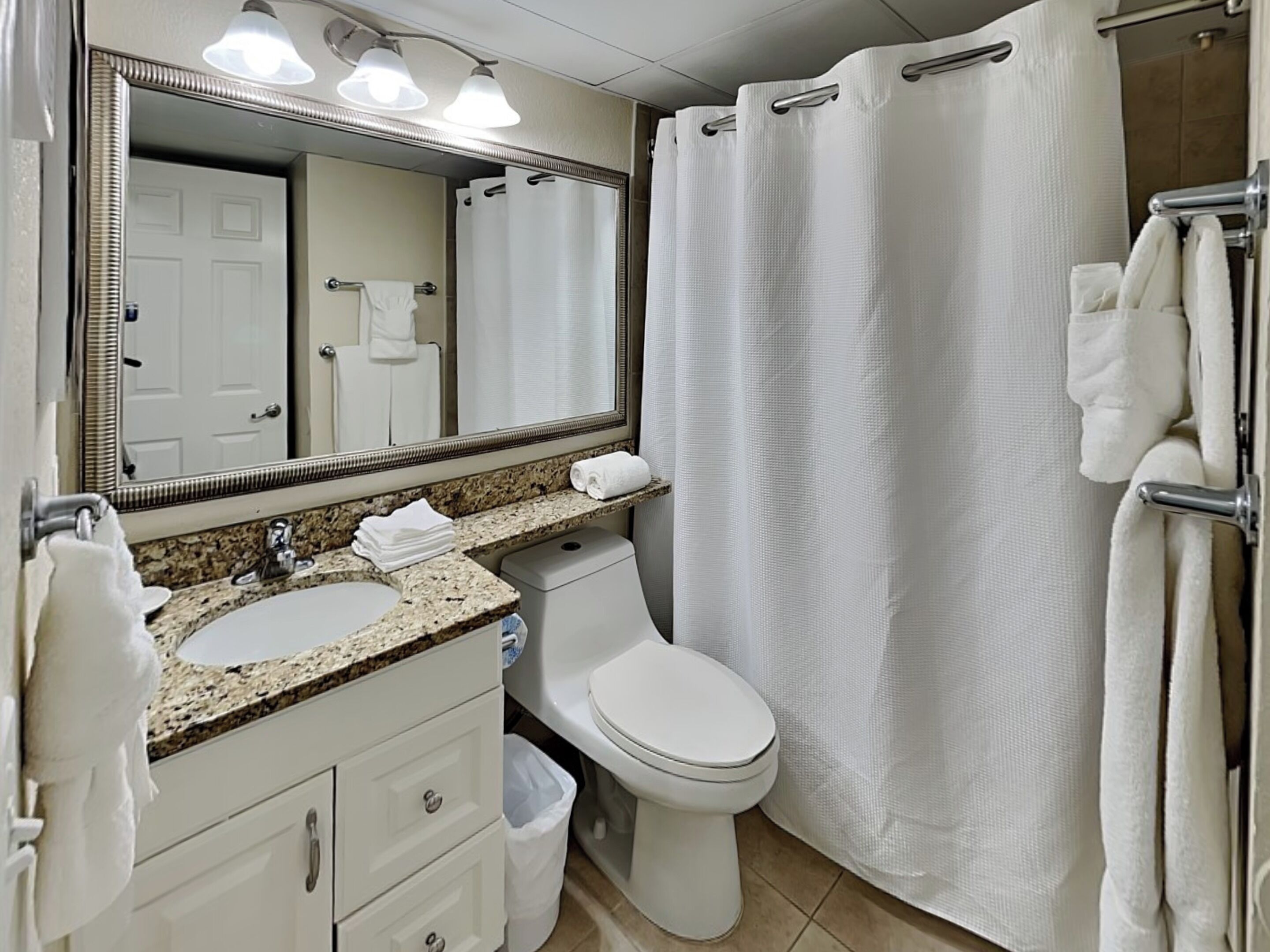 Un baño con lavamanos, inodoro y cortina de ducha.