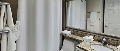 A bathroom with a shower curtain, a toilet, a sink, and a mirror.