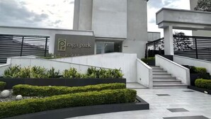 A modern building with a sign reading 'Raga Park,' featuring a staircase, landscaped areas, and a minimalist design.