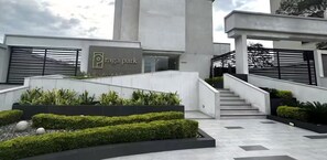 A modern building with a sign reading 'Raga Park,' featuring a staircase, landscaped areas, and a minimalist design.