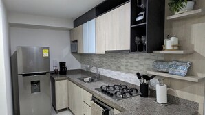 A modern kitchen with a stainless steel refrigerator, a gas stove, and a microwave.