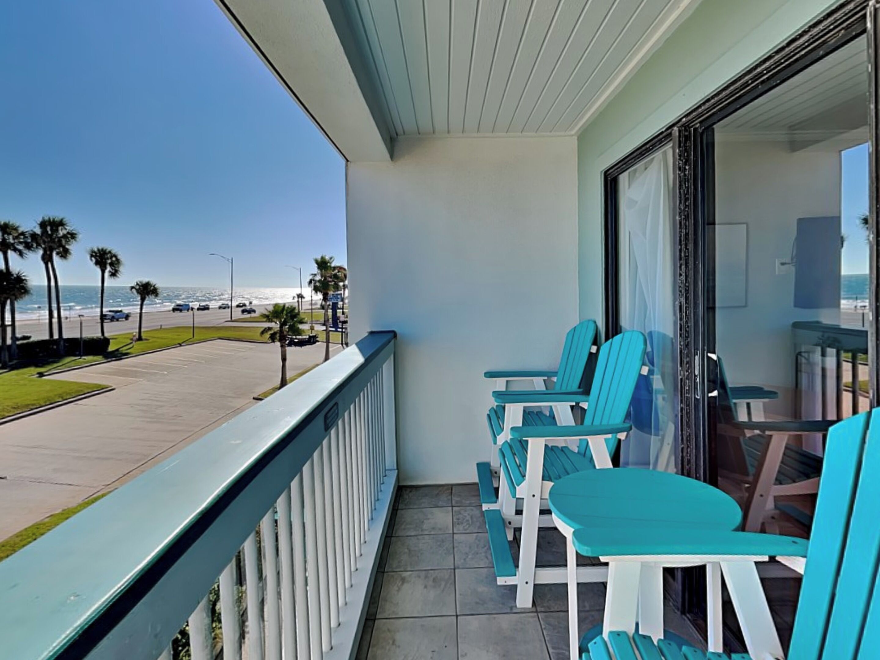 Un balcón con vista a la playa, que incluye una mesa y sillas.