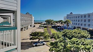 A hotel with a pool area, a parking lot, and a view of the ocean. - Casa Del Mar 211 (Galveston)