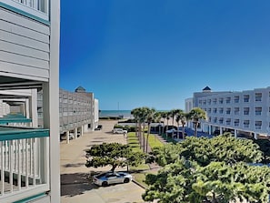 A hotel with a pool area, a parking lot, and a view of the ocean. - Casa Del Mar 211 (Galveston)