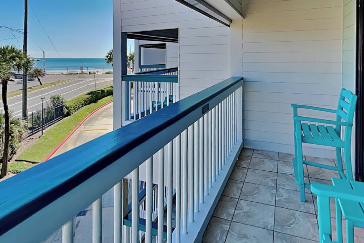 A balcony with a view of the beach and road.
