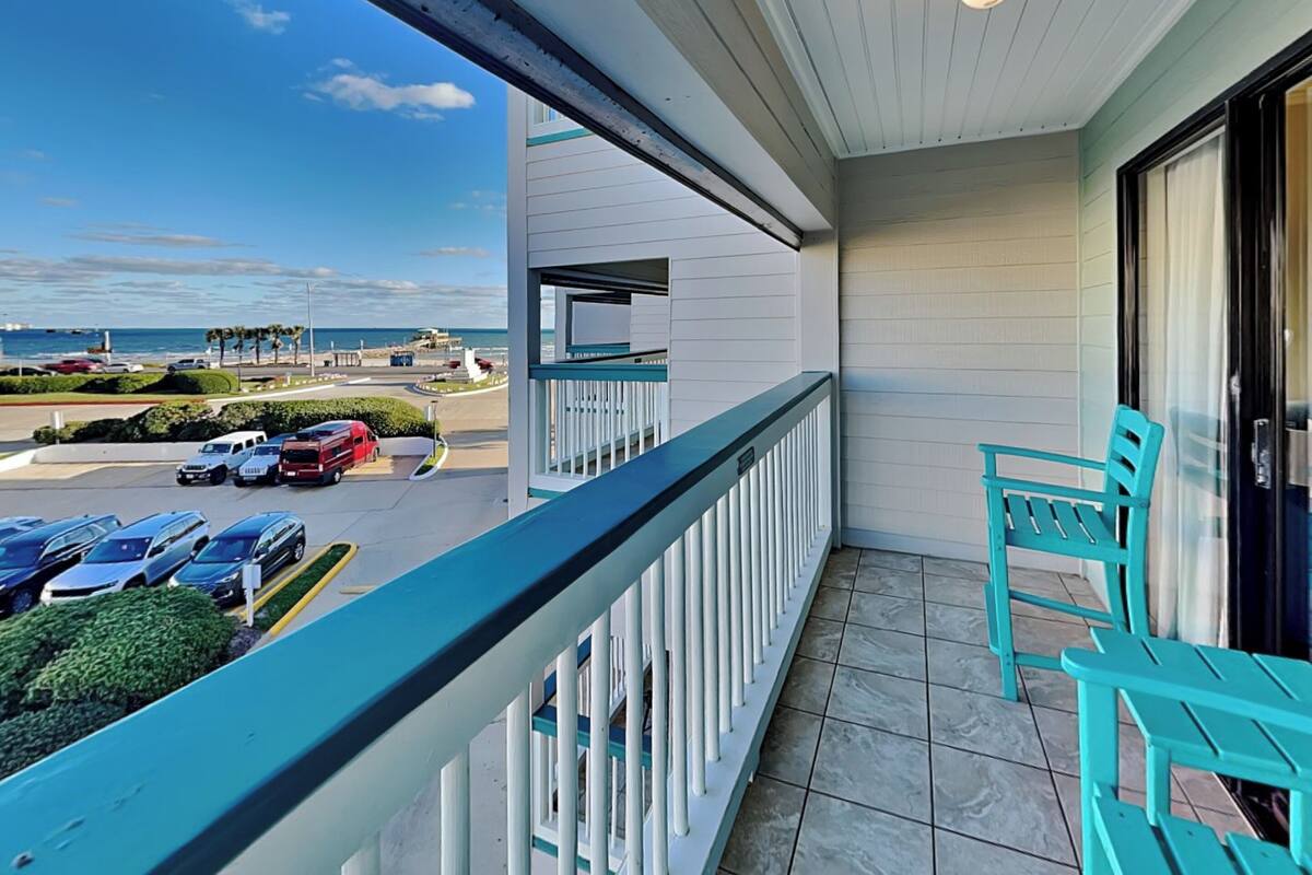 A balcony with a view of a parking lot and beach.