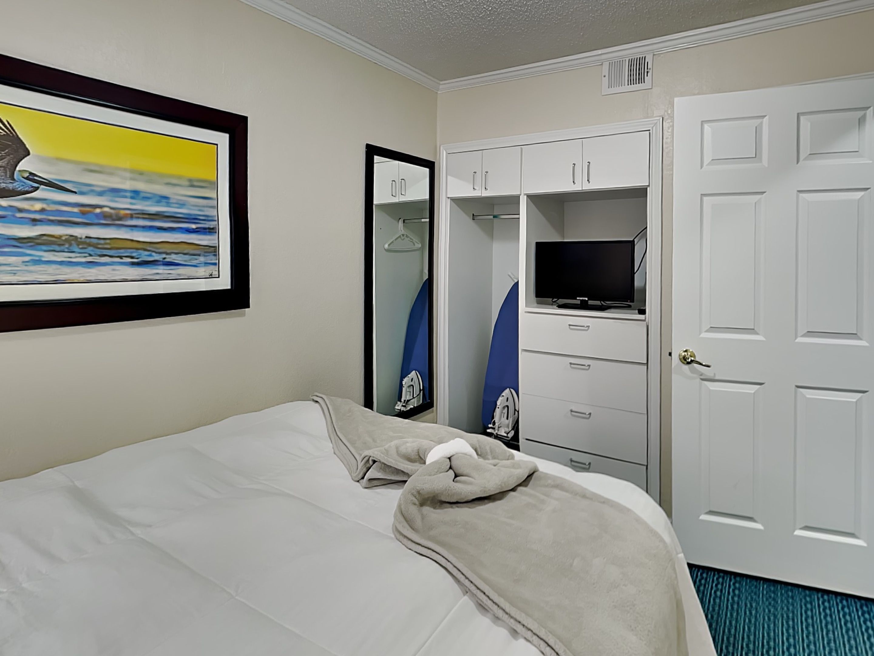 A hotel room with a bed, a TV, a wardrobe, and a mirror.