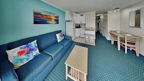 A compact living space with a sofa, a small table, a kitchenette, and a dining area. - Casa Del Mar 3 by Ryson Vacation Rentals (Galveston)