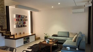 Uma sala de estar moderna com sofá, mesa de centro, estante e área de jantar.
