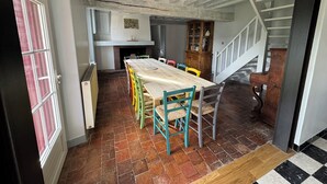 Ein Essbereich mit einem Holztisch, bunten Stühlen, einem Kamin und einer Treppe, die nach oben führt.