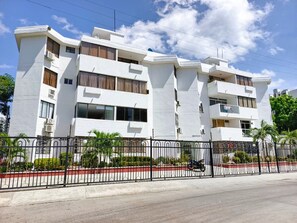 Un immeuble moderne à plusieurs étages, doté d’une façade blanche, de grandes fenêtres et de balcons.