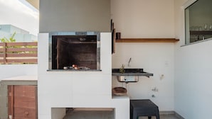A compact kitchen with a built-in grill, a small sink, and a wooden shelf. - House w/ 3 Bedrooms and Barbecue Lpb0000 (Garopaba)