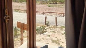A room with a view of a desert landscape through a window. - Cabañas La Nochera (Tilcara)