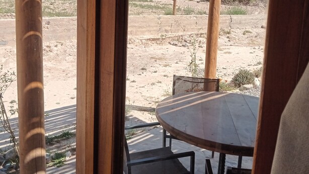 A wooden pergola with a table and chairs, overlooking a desert landscape with mountains in the background. - Cabañas La Nochera (Tilcara)