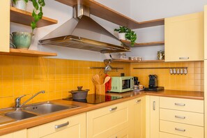 A kitchen with yellow cabinets, a stainless steel sink, a microwave, and a stove. - Sesto Sole - wide 6th Floor Apart near Prada-Bocconi-IEO (Milano)