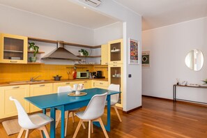 A compact kitchen with a blue table and white chairs, a microwave, and a sink. - Sesto Sole - wide 6th Floor Apart near Prada-Bocconi-IEO (Milano)