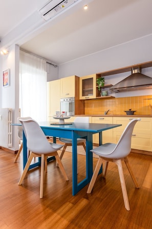Eine moderne Küche mit einem blauen Tisch, weißen Stühlen und einer Edelstahl-Dunstabzugshaube.