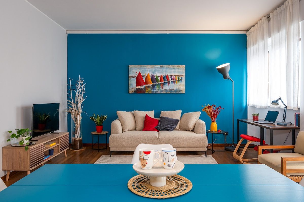 A living room with a blue wall, a sofa, a coffee table, a TV, and a painting.