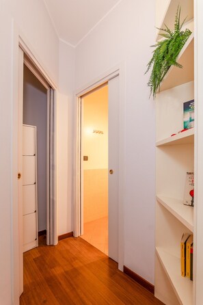 A hallway with a wooden floor, white walls, and a bookshelf with books. - Sesto Sole - wide 6th Floor Apart near Prada-Bocconi-IEO (Milano)