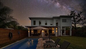 Ein modernes Haus mit Schwimmbad, Außenbereich und einer Terrasse unter einem Sternenhimmel.