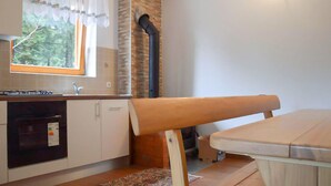 A compact kitchen with a stove, sink, and cabinets. There's a window with curtains and a view of greenery outside. - 2 bedroom nice apartment in Mrkopalj (Mrkopalj)