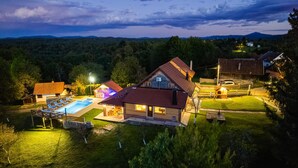 Una casa grande con piscina, zona de barbacoa y espacio exterior bien iluminado.