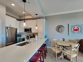 Una cocina moderna con gabinetes blancos, electrodomésticos de acero inoxidable y una isla grande con taburetes de bar.