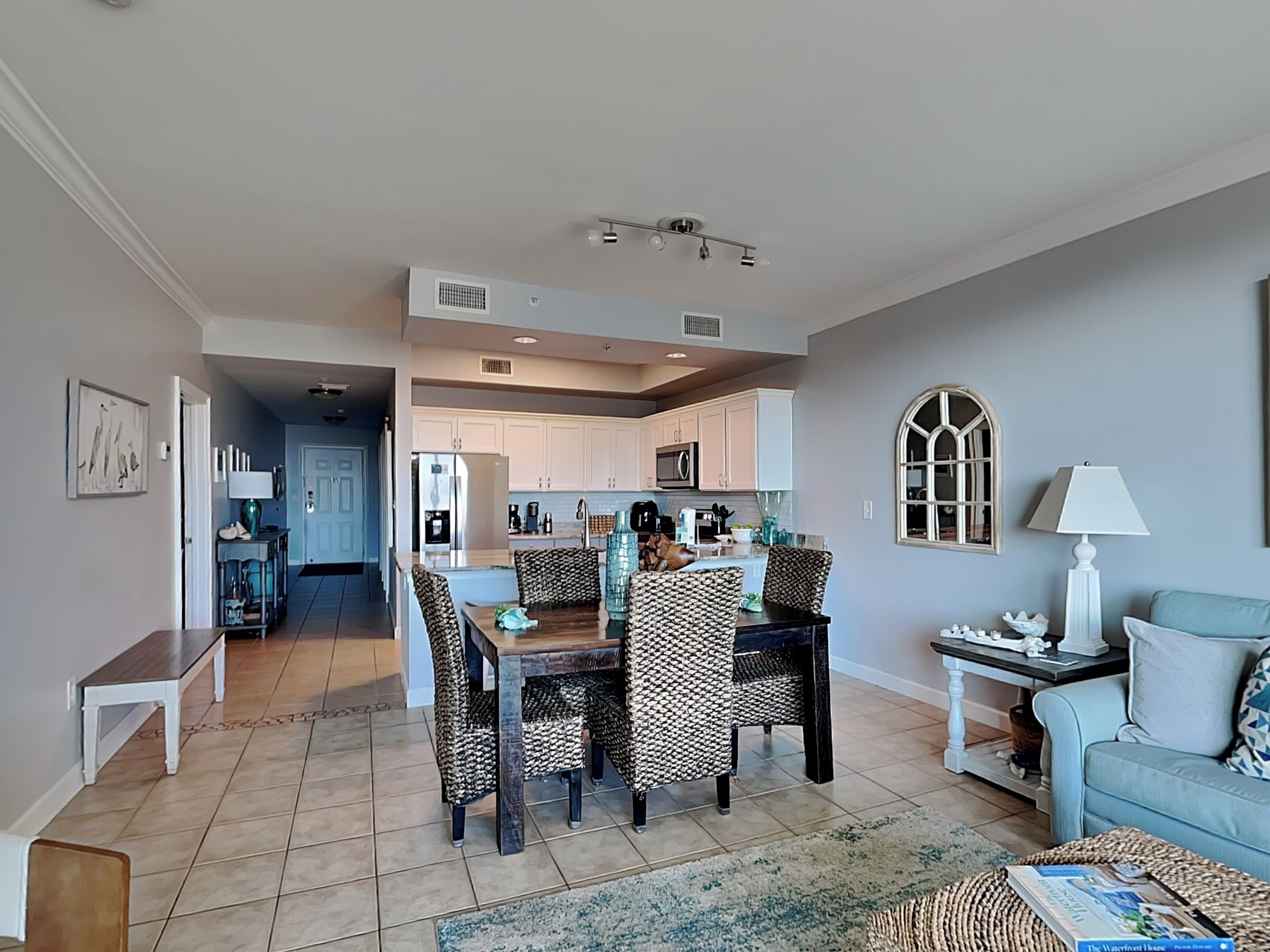 A spacious living room with a dining area, a kitchen in the background, and a cozy seating area with a lamp and a sofa.