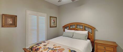 A bedroom with a bed, a nightstand, a ceiling fan, and two wall-mounted picture frames.