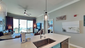Eine moderne Küche mit einer großen Kochinsel, einem Deckenventilator und Blick auf den Wohnbereich.