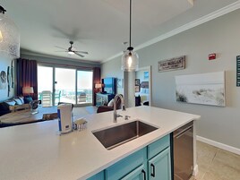 Una cocina moderna con una isla grande, un ventilador de techo y vistas al área de estar.