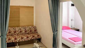 A room with a floral sofa, a bed with pink bedding, and a glass table. - Apartment in Novalja (127) (Novalja)