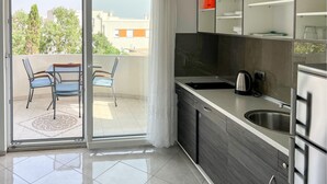 Et moderne køkken med en skydedør til en balkon med to stole og et bord.