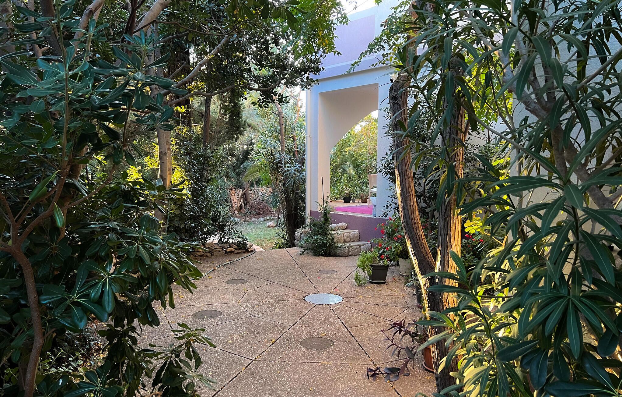 Un chemin de jardin menant à un bâtiment doté d’un mur en pierre et d’un tapis rouge.