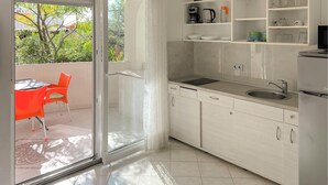 Cozinha moderna com porta de vidro deslizante que dá para área externa, pia e mesa de jantar com cadeiras.