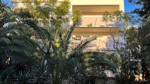 Um edifício de vários andares com varandas, rodeado por vegetação tropical exuberante.