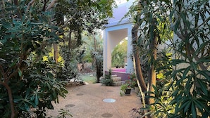 Caminho de jardim que leva a um edifício com parede de pedra e tapete vermelho.
